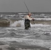 Fisherman in the sea with rod wearing Vass hybrid waders